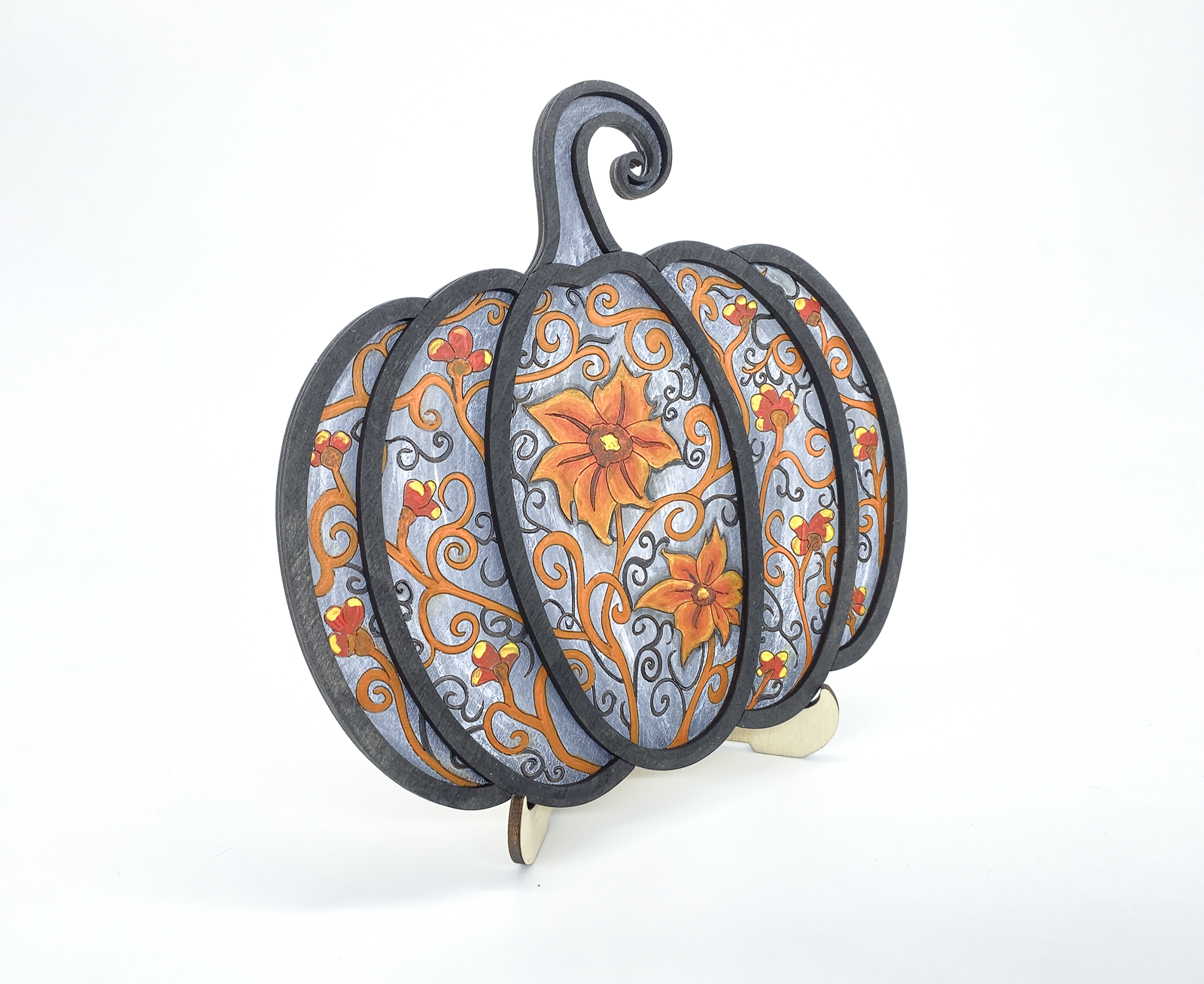 Angled view of painted gothic pumpkin wood art showing layered scrollwork detail and dimension