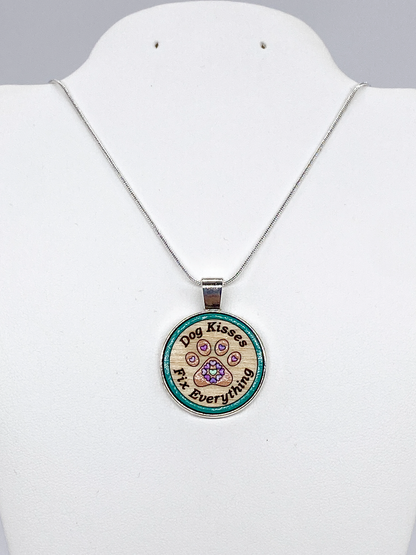 Close-up of round Baltic birch wood pendant featuring a paw print with heart details inside a silver bezel setting.