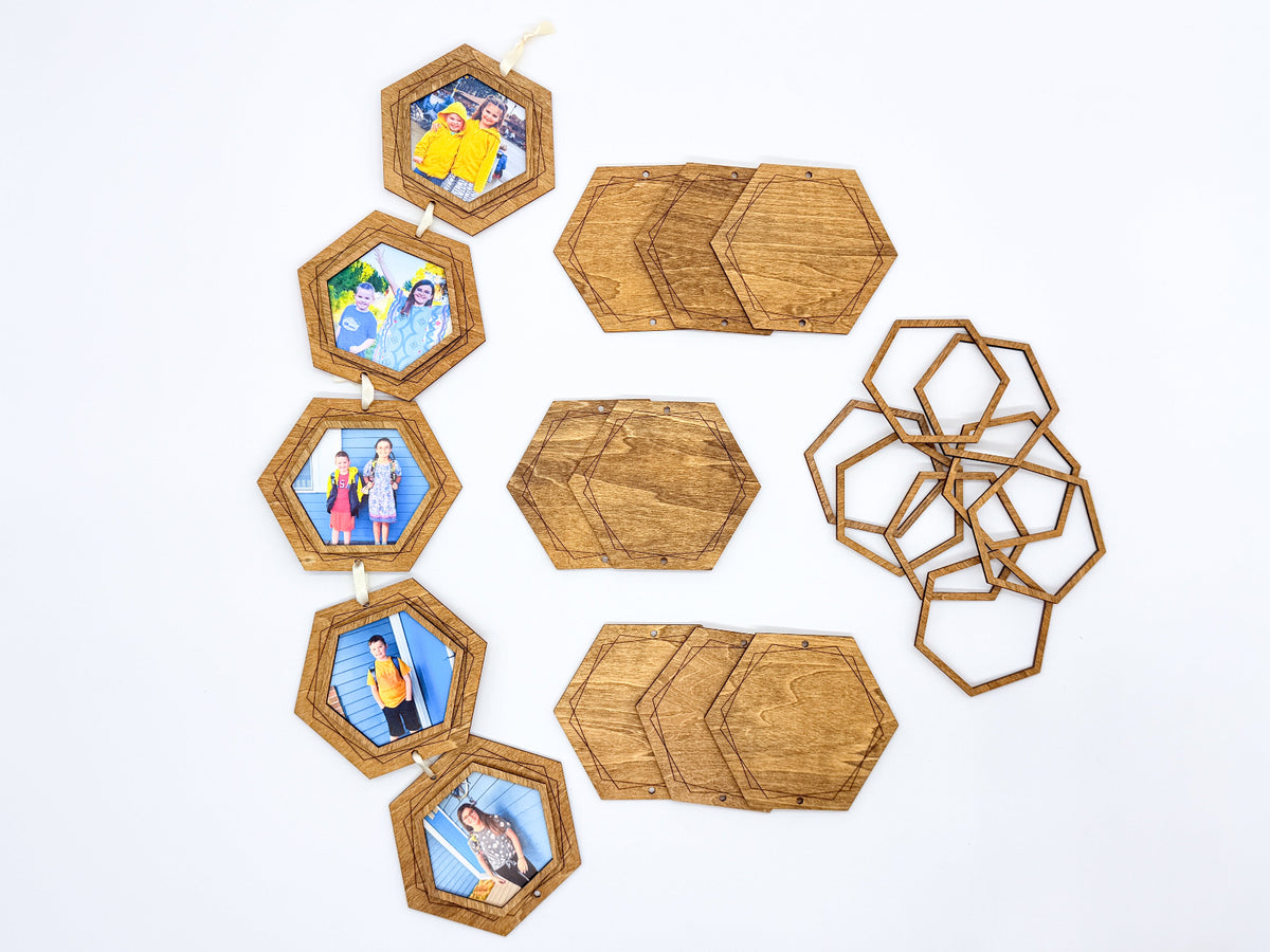 Overhead view of five finished hexagon photo frames linked with ribbon, with additional stained wooden backings and open frame pieces arranged alongside.
