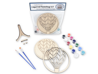 Packaged Hot Air Balloon layered painting kit with unfinished wood artwork, paint pots, brushes, glue, stand, and display hardware.
