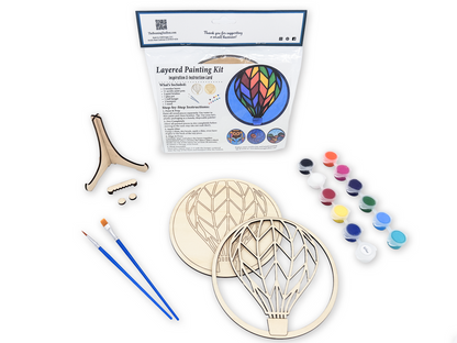 Hot Air Balloon layered wood painting kit with unfinished wood pieces, paint pots, brushes, glue, display stand, and packaging.