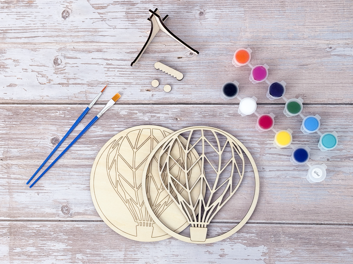 Finished Hot Air Balloon layered wood artwork painted in bright rainbow colors and displayed on a small wooden stand.
