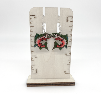 Earrings with fish design on a wooden stand with measurement scale