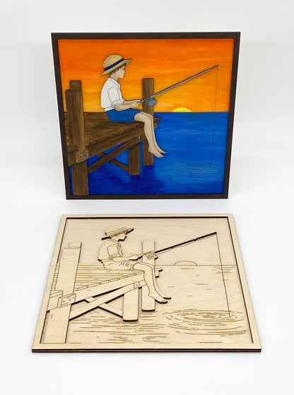 Framed artwork of a boy fishing with a laser-cut wooden model below on a white background