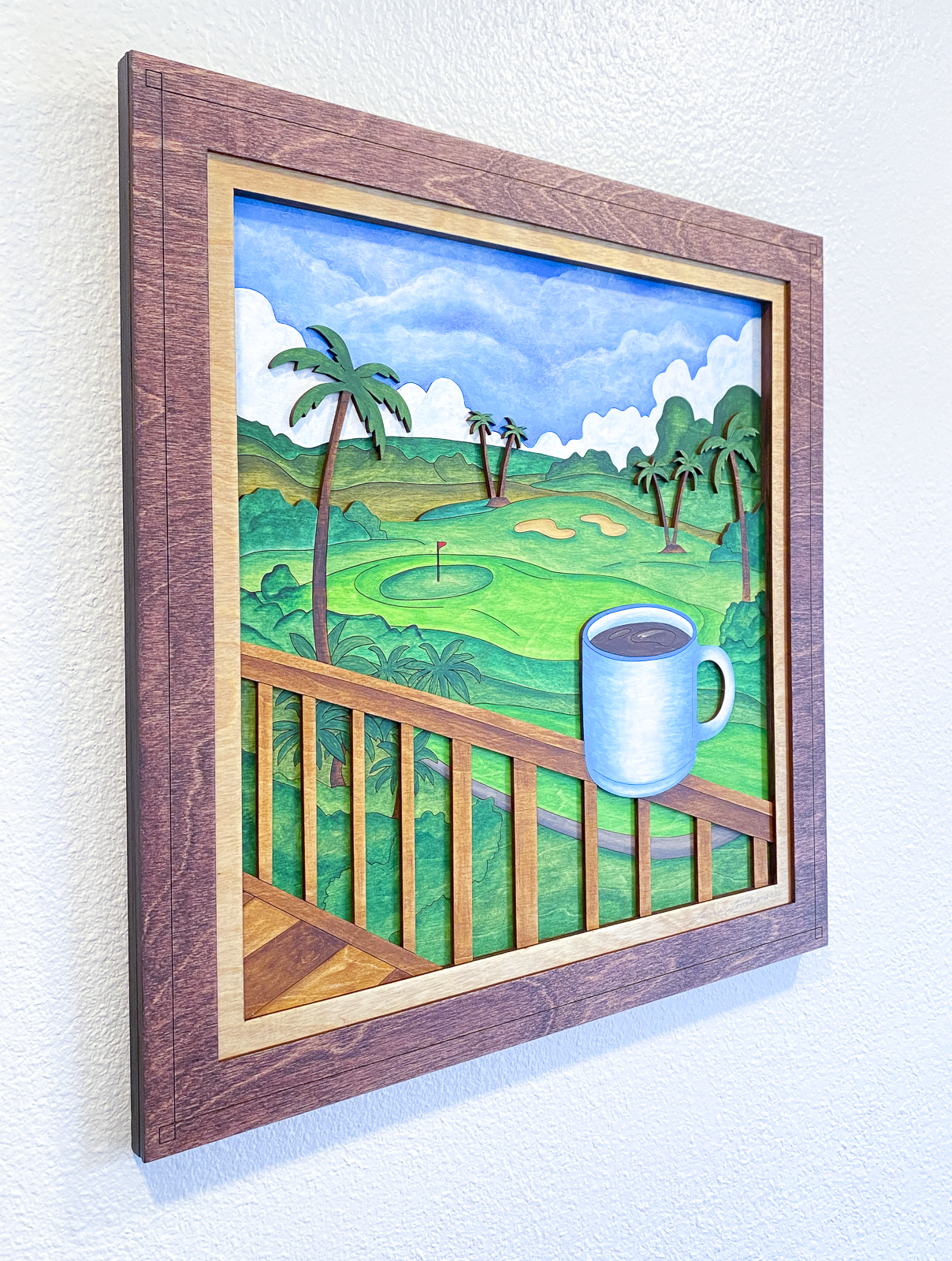 Angled left-side view of Lanai Mornings layered sculptural wood artwork showing dimensional tropical landscape layers, palm trees, and coffee cup details within a stained wood frame.