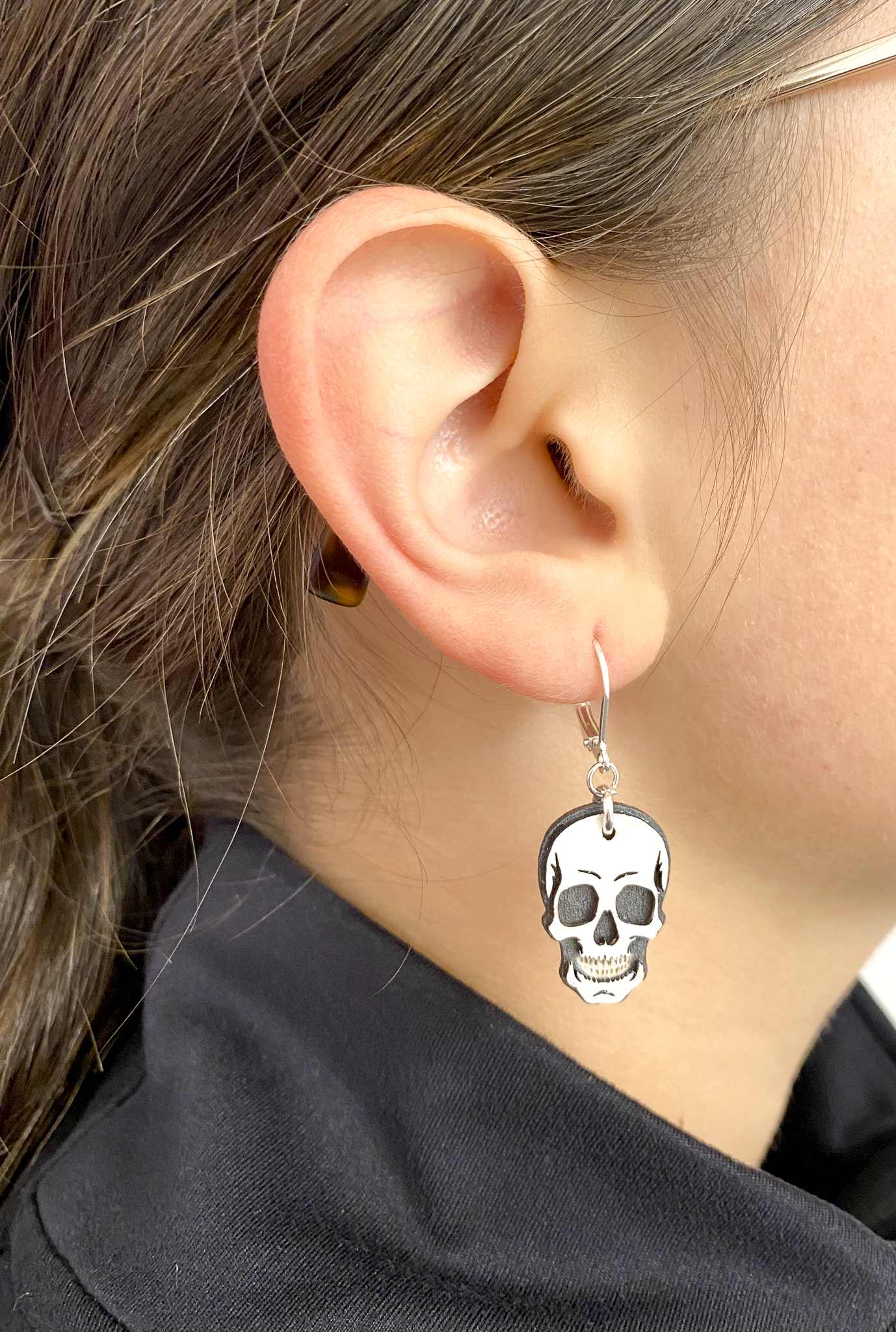 Hand-painted layered wood skull earring worn on the ear to show size and style.