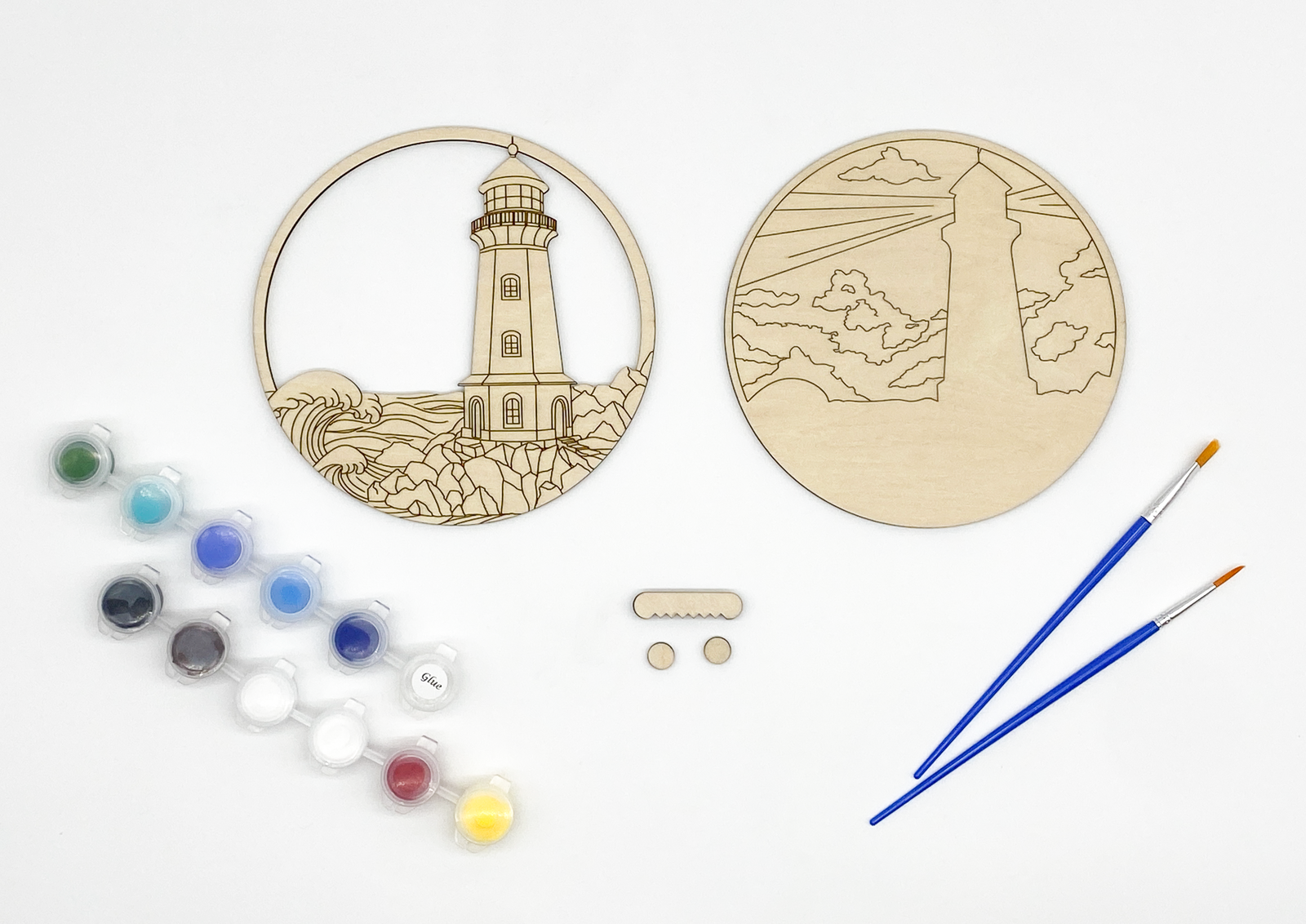 Lighthouse DIY paint kit contents showing two unpainted wood layers, paint pots, brushes, wall hanger, and bumpers