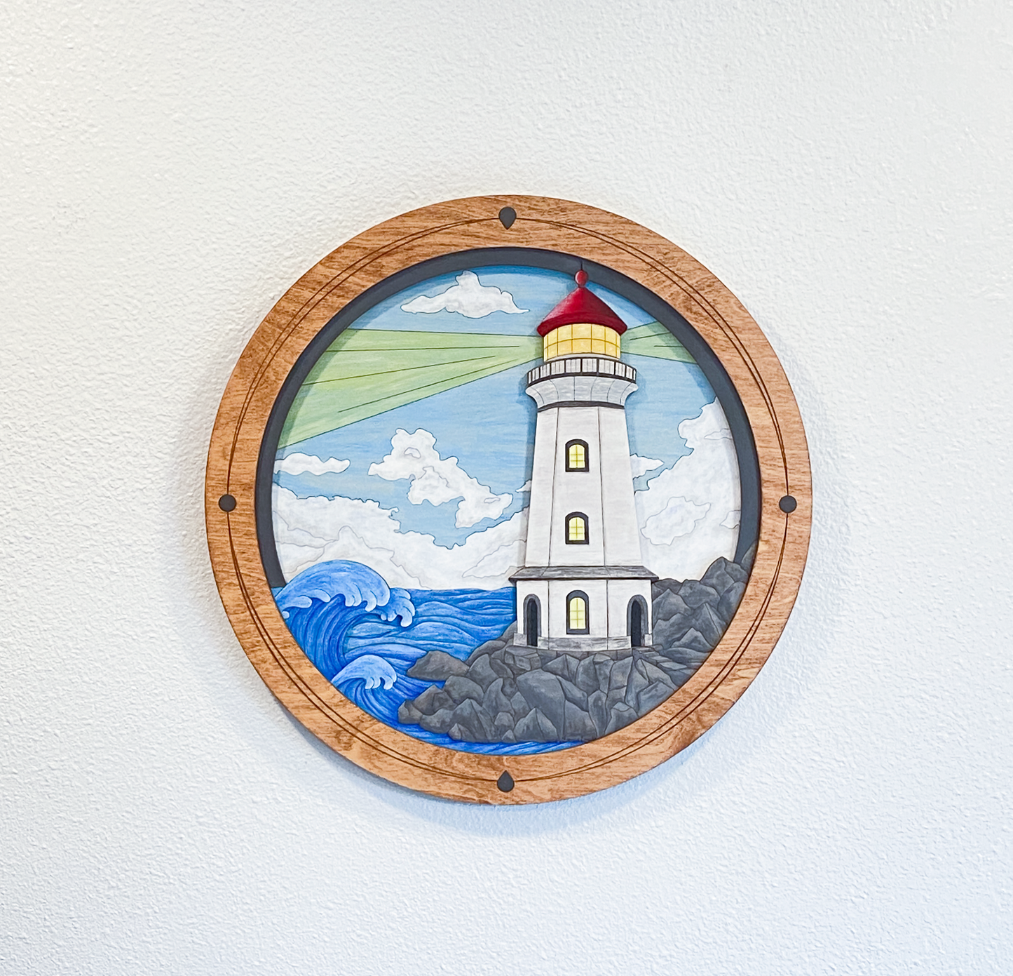 A full view of the finished "Lighthouse on a Rocky Shore" piece in a studio setting, showcasing the vibrant colors and custom-built circular frame.