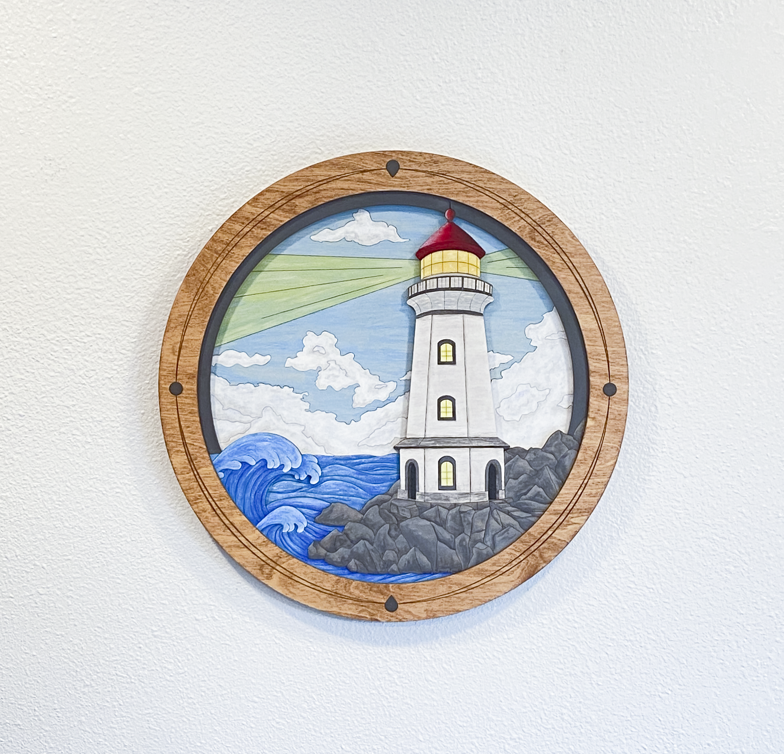 A full view of the finished "Lighthouse on a Rocky Shore" piece in a studio setting, showcasing the vibrant colors and custom-built circular frame.