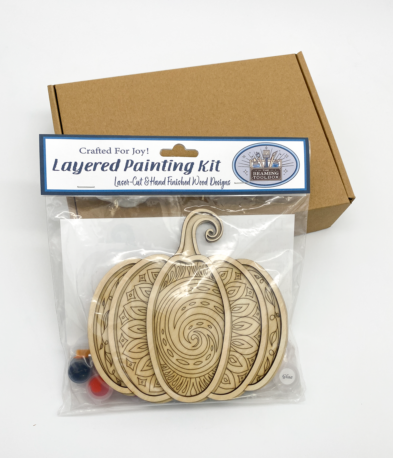 Front of Pumpkin Mandala DIY paint kit packaging showing layered wood mandala pumpkin design and included painting supplies