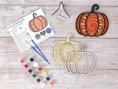 Mandala Pumpkin DIY wood painting kit with unfinished layers, paint pots, brushes, display stand, packaging, and a finished painted example.
