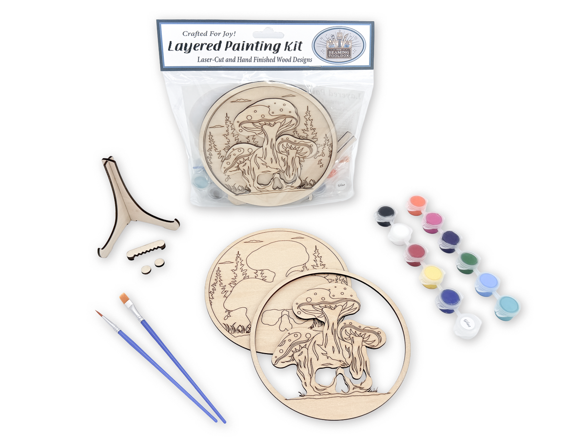 Mushroom Skull layered painting kit with unfinished wood pieces, paint pots, brushes, glue, display stand, hardware, and instruction card in packaging.
