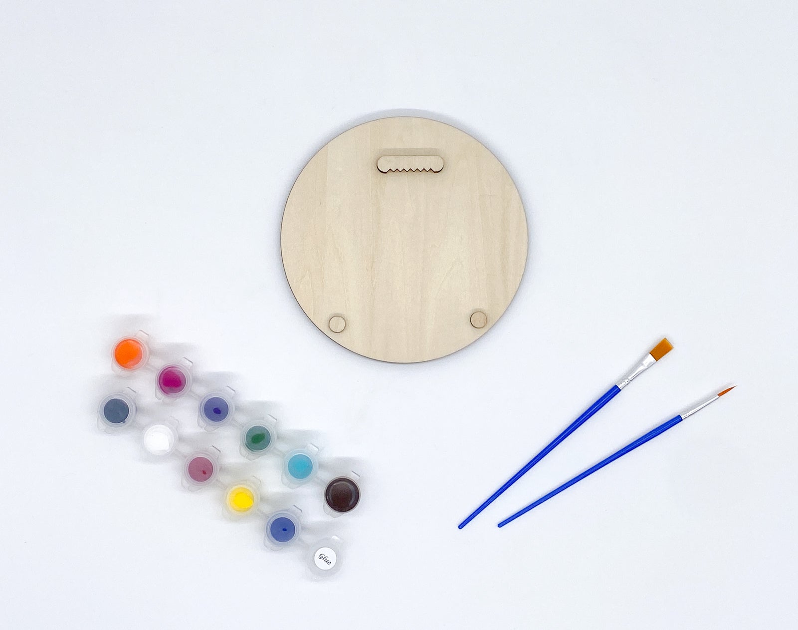 Backside of diy paint kit, showing placement of sawtooth hangers and bumpers, showing paints and brushes