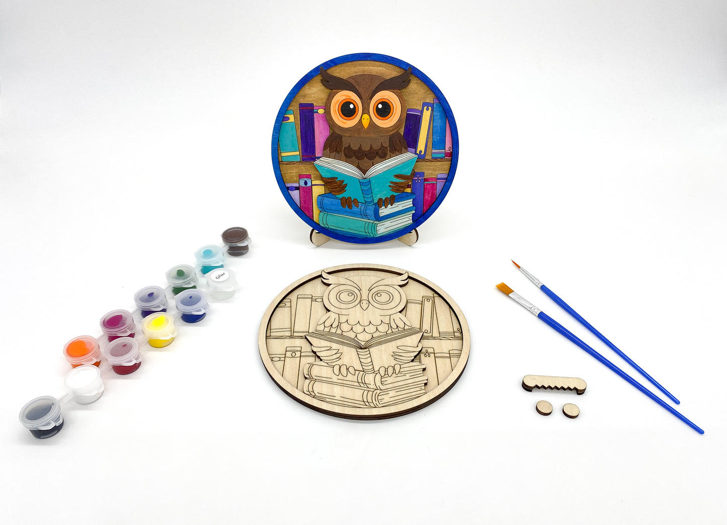 Wooden craft kit with owl design, paint cans, and brushes on a white background