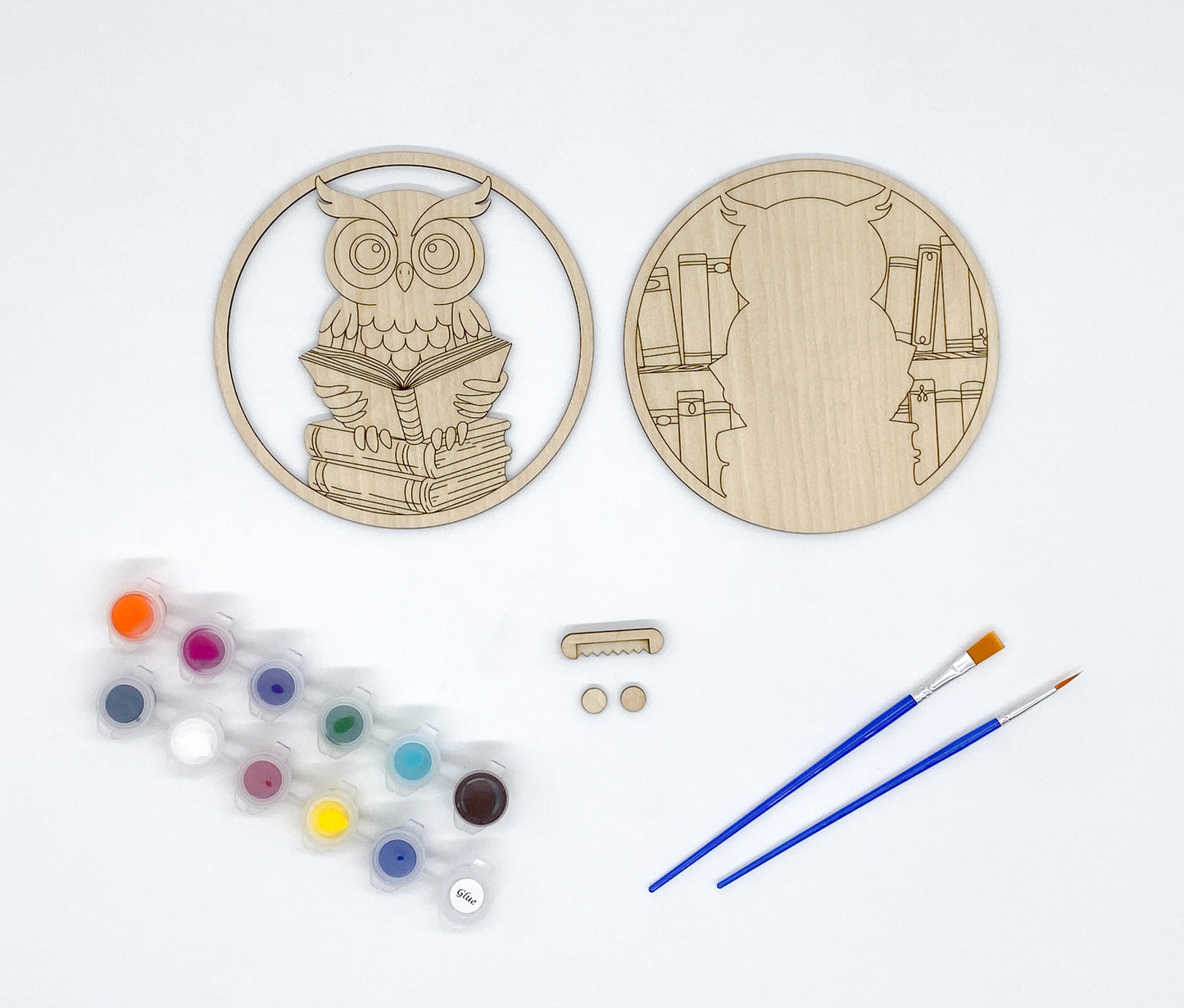 Wooden owl-shaped craft kit with paint, brushes, sawtooth wall hanger and bumpers on a white background