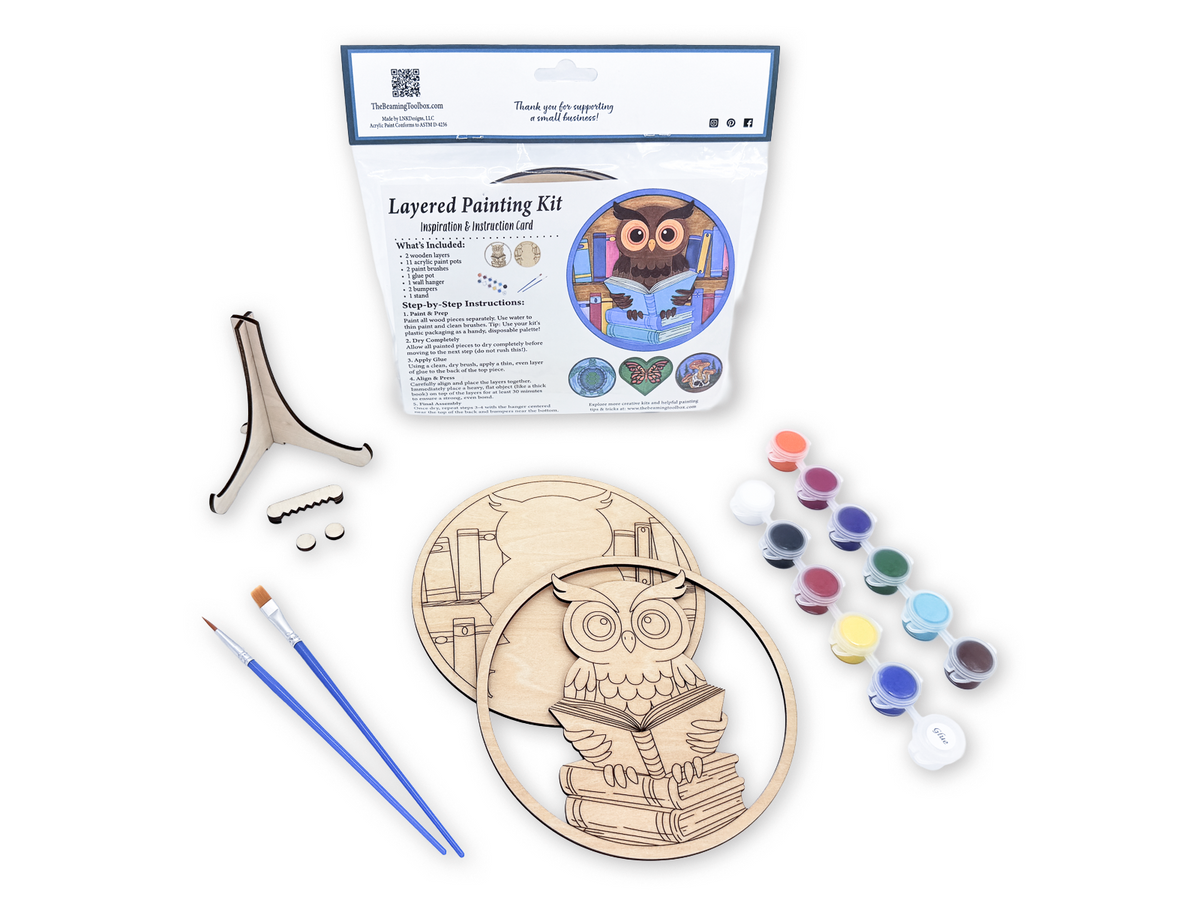 Book lovers owl layered wood painting kit in packaging with unfinished wood pieces, paint pots, brushes, glue, and display hardware.