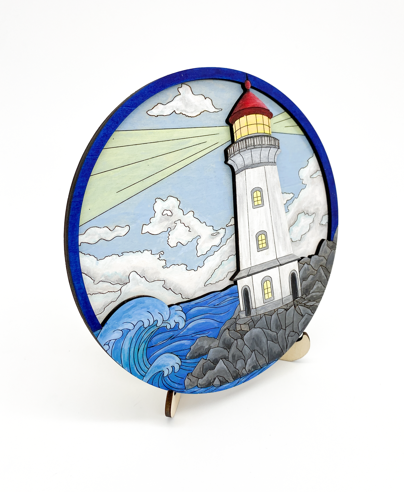 Side angle view of finished painted lighthouse layered wood art showing depth of layers and ocean scene