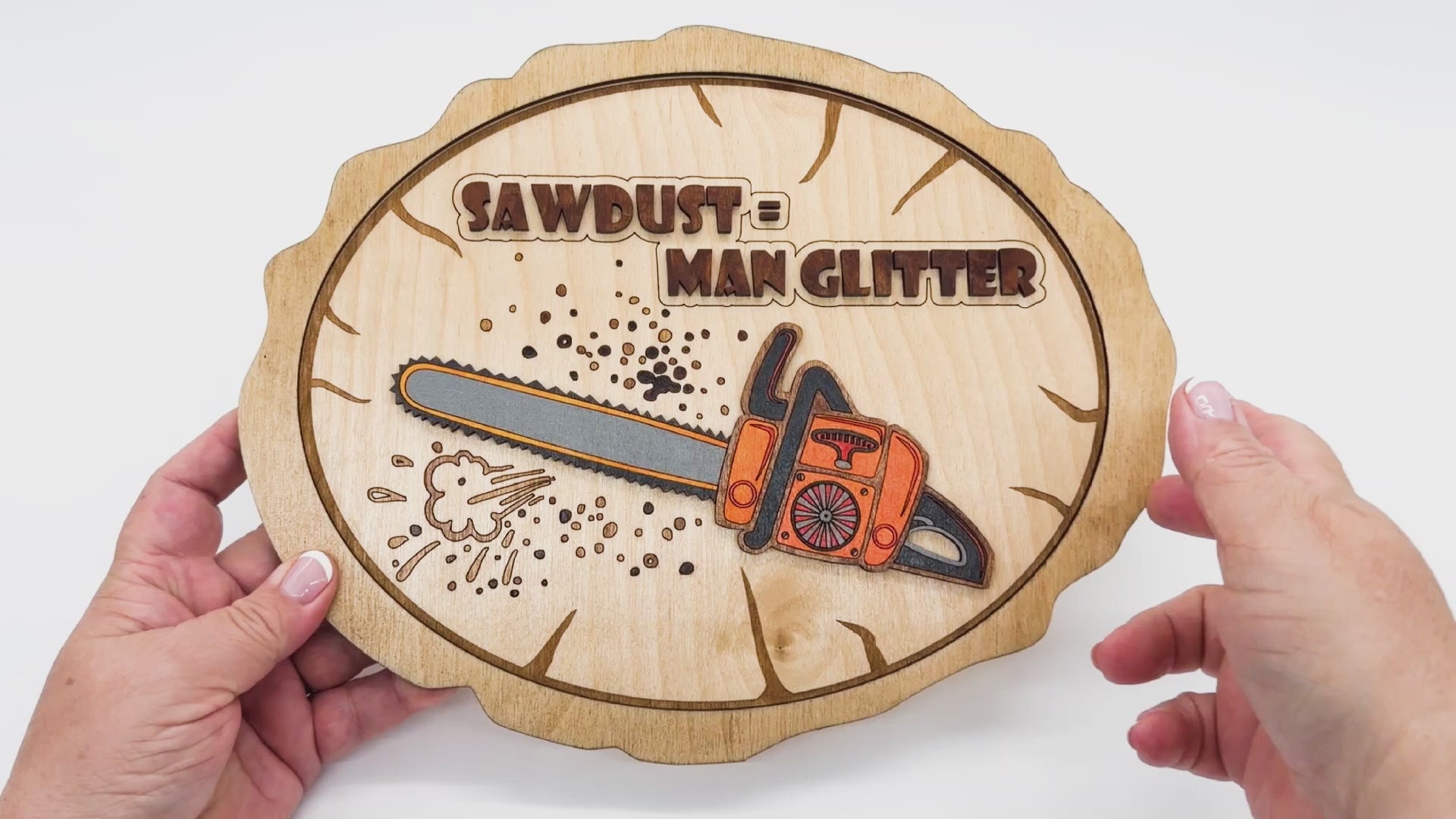 Video of Sawdust Equals Man Glitter showing the front and back with a colored chainsaw on front of a sign that is a faux wood round.