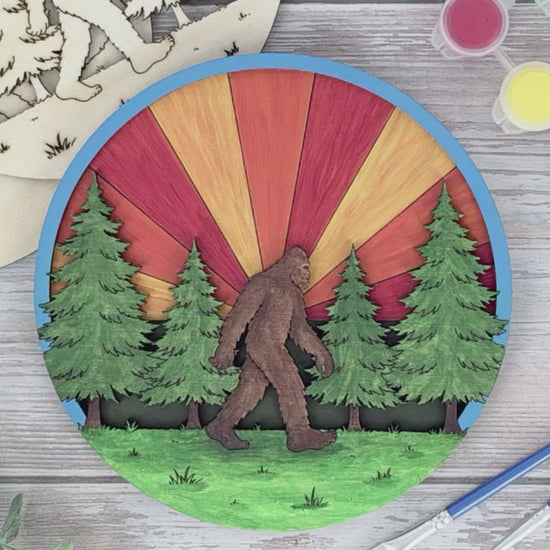 Video showing a Sasquatch layered wood adult craft kit being hand painted with bright acrylic colors on the engraved forest design.