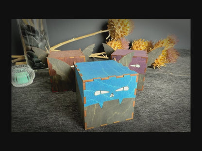 Video description: Handmade wooden bat keepsake boxes in blue, brown, and purple, featuring decorative bat wings, engraved faces, and hinged lids for storing small treasures.