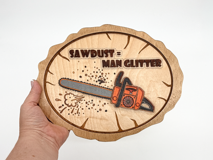 Hand holding Sawdust = Man Glitter layered wood wall art with an orange chainsaw design to show the finished size.