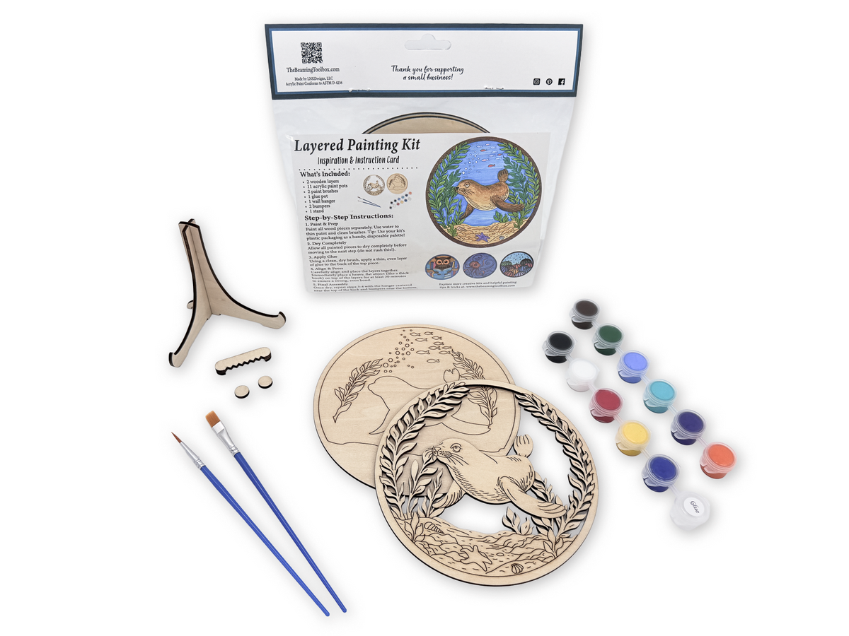 Complete Sea Lion adult painting kit with unfinished layered wood pieces, paint pots, brushes, glue, display stand, hardware, and packaged guide.
