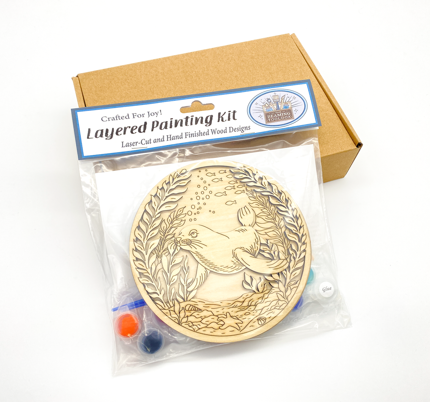 Sea lion DIY paint kit packaged in clear bag with label, showing layered wood pieces, paint pots and brushes inside