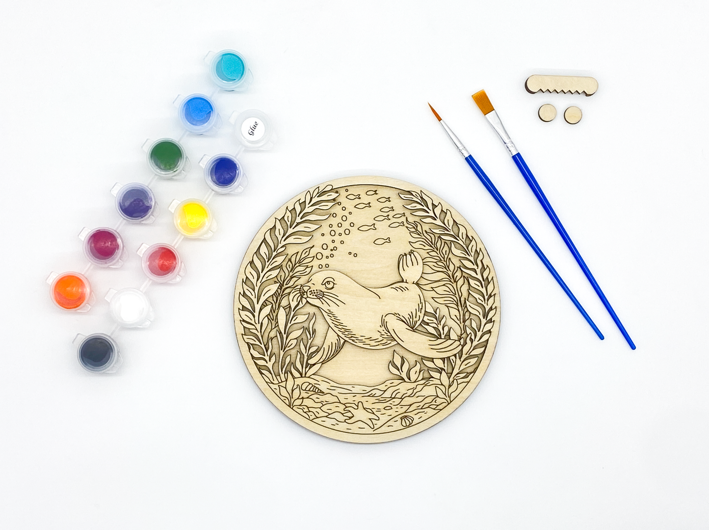 Unpainted sea lion layered wood paint kit with stacked wood pieces, paint pots, brushes and hanging hardware on white background