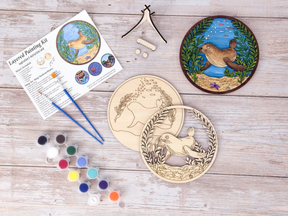 Sea Lion DIY wood painting kit with unfinished layers, paint pots, brushes, display stand, packaging, and a finished painted example.