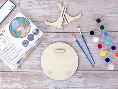 Back of the Sea Lion wood craft kit showing the hanger piece, small bumpers, paint pots, brushes, display stand, and packaging.