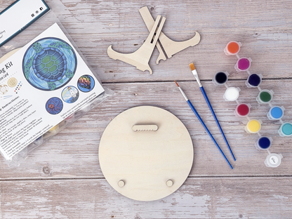 Sea turtle adult craft kit supplies with paint pots, brushes, wood display stand pieces, packaged kit, and round wood backing.