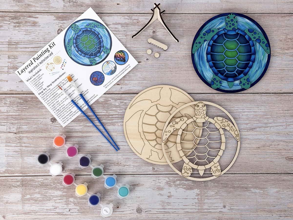 Sea turtle gift kit with finished colorful turtle artwork, unpainted wood layers, instruction card, paint pots, brushes, and stand pieces.