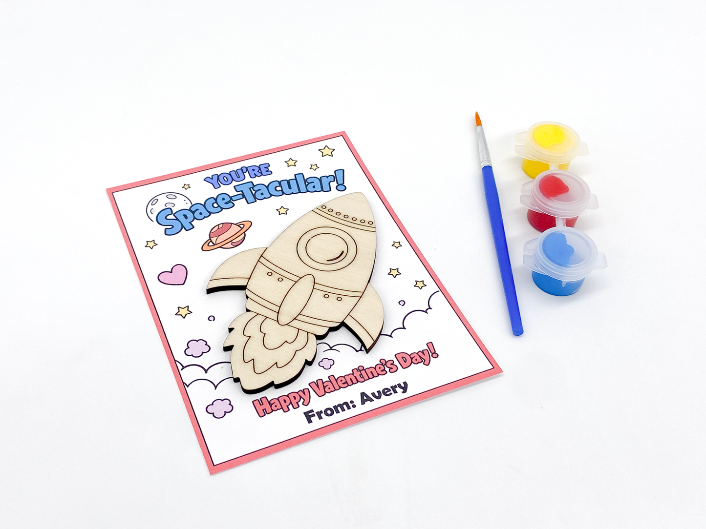Valentine's Day card with space-themed design and paint supplies on a white background