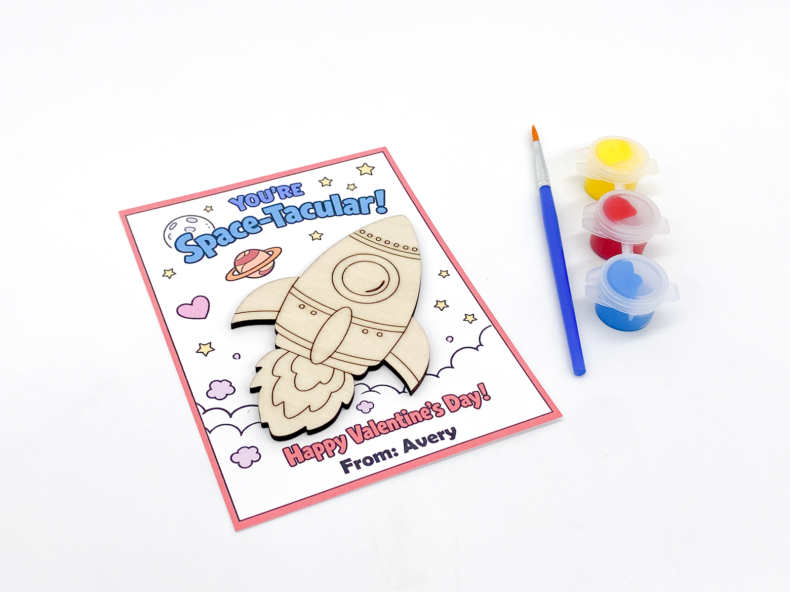 Valentine's Day card with space-themed design and paint supplies on a white background