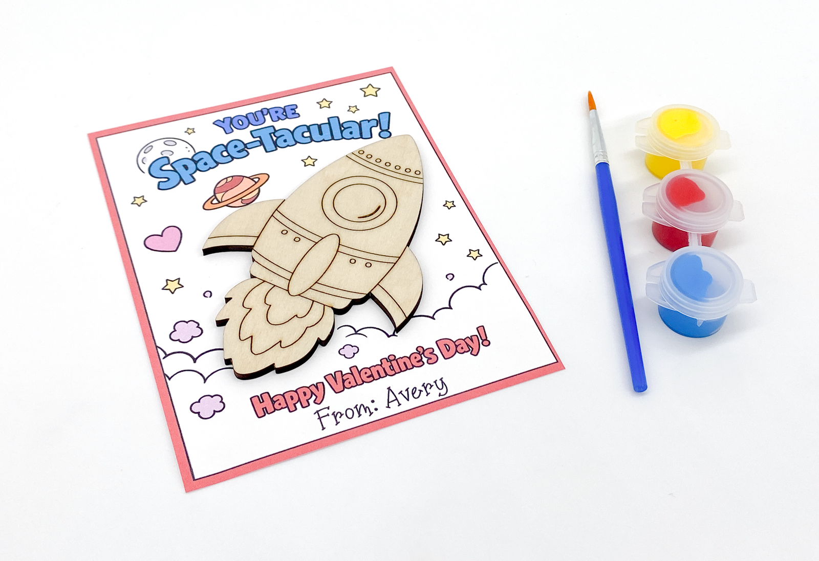 Valentine's Day card with space-themed design and paint supplies on a white background