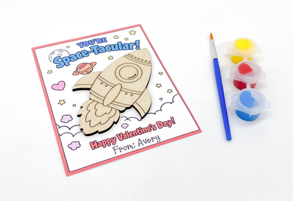 Valentine's Day card with space-themed design and paint supplies on a white background