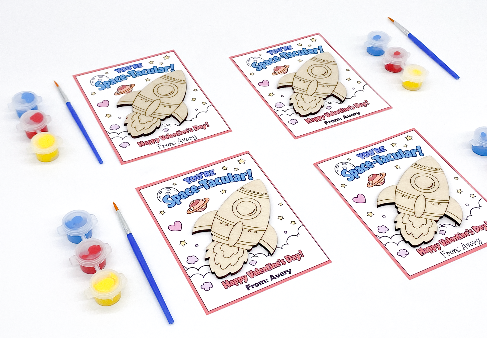 Four Valentine's Day cards with space-themed designs and coloring supplies on a white background.