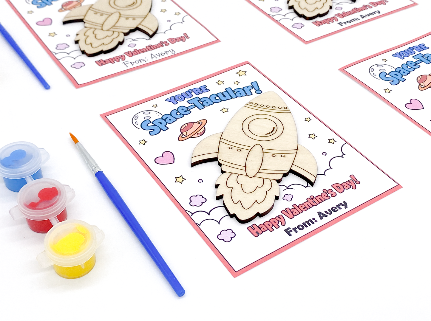 Valentine's Day card with space-themed design and paint supplies on a white background