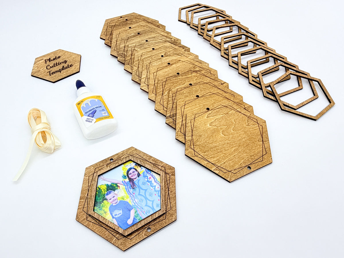 A set of hexagonal wooden photo frames and matching wooden mounting pieces arranged on a white background, along with a small bottle of white glue, a roll of beige cord, and a small engraved wooden plaque reading 'Photo Cutting Template'.