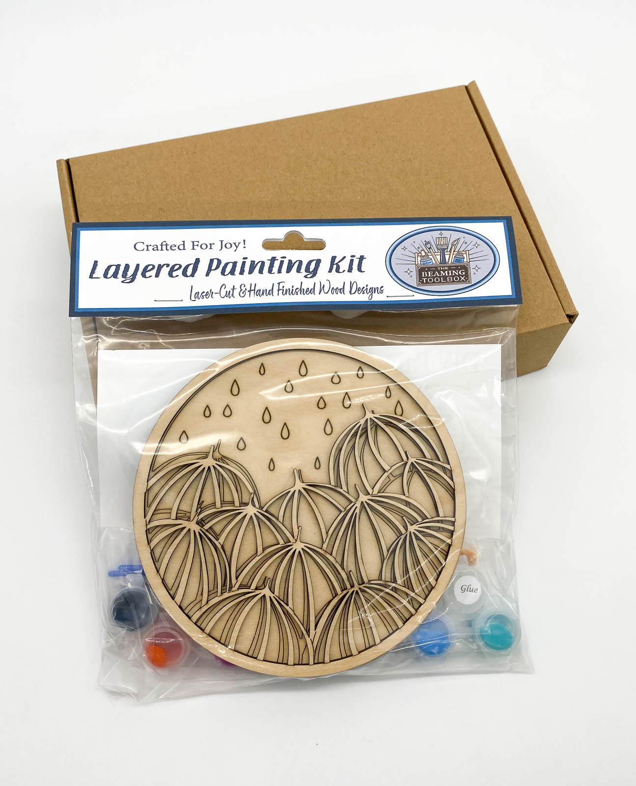 Front of Umbrellas DIY paint kit packaging showing layered wood umbrellas design and included painting supplies