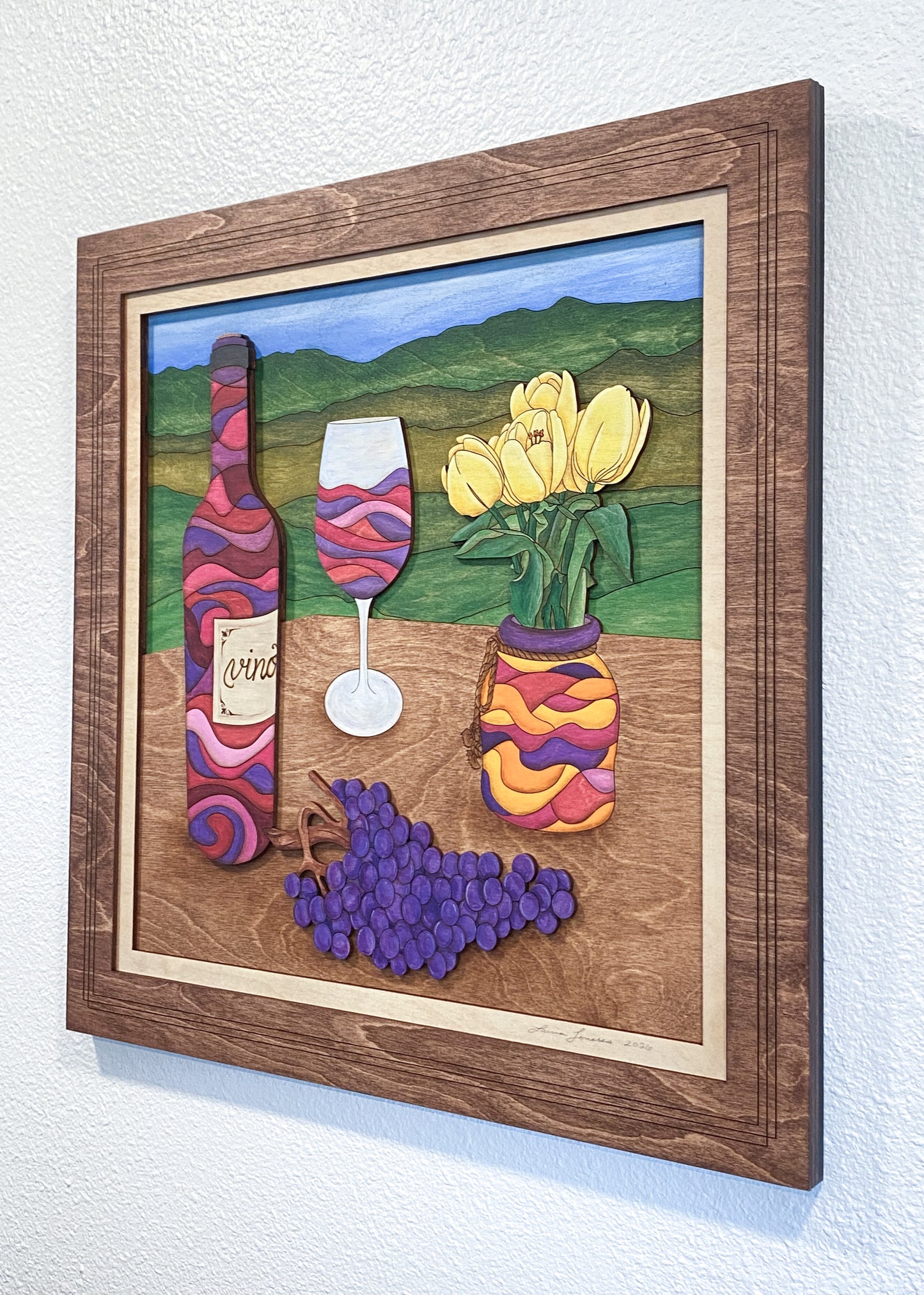 Decorative wall art with wine bottle, glass, and flowers in a wooden frame.