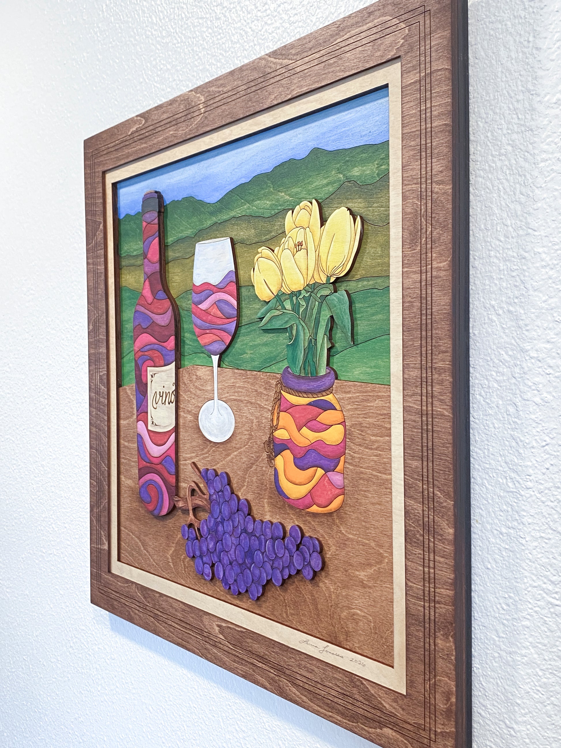 Framed artwork of a colorful wine-themed scene with bottles, grapes, and tulips.
