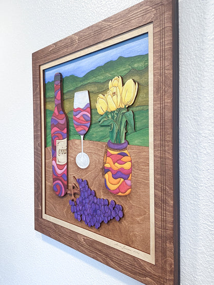 Framed artwork of a colorful wine-themed scene with bottles, grapes, and tulips.