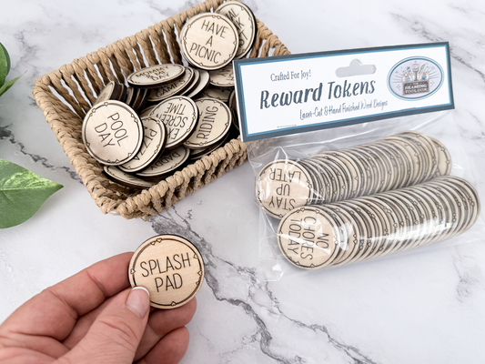 Wooden kids reward token set with engraved activity coins, packaged tokens, and a Splash Pad token held in hand.