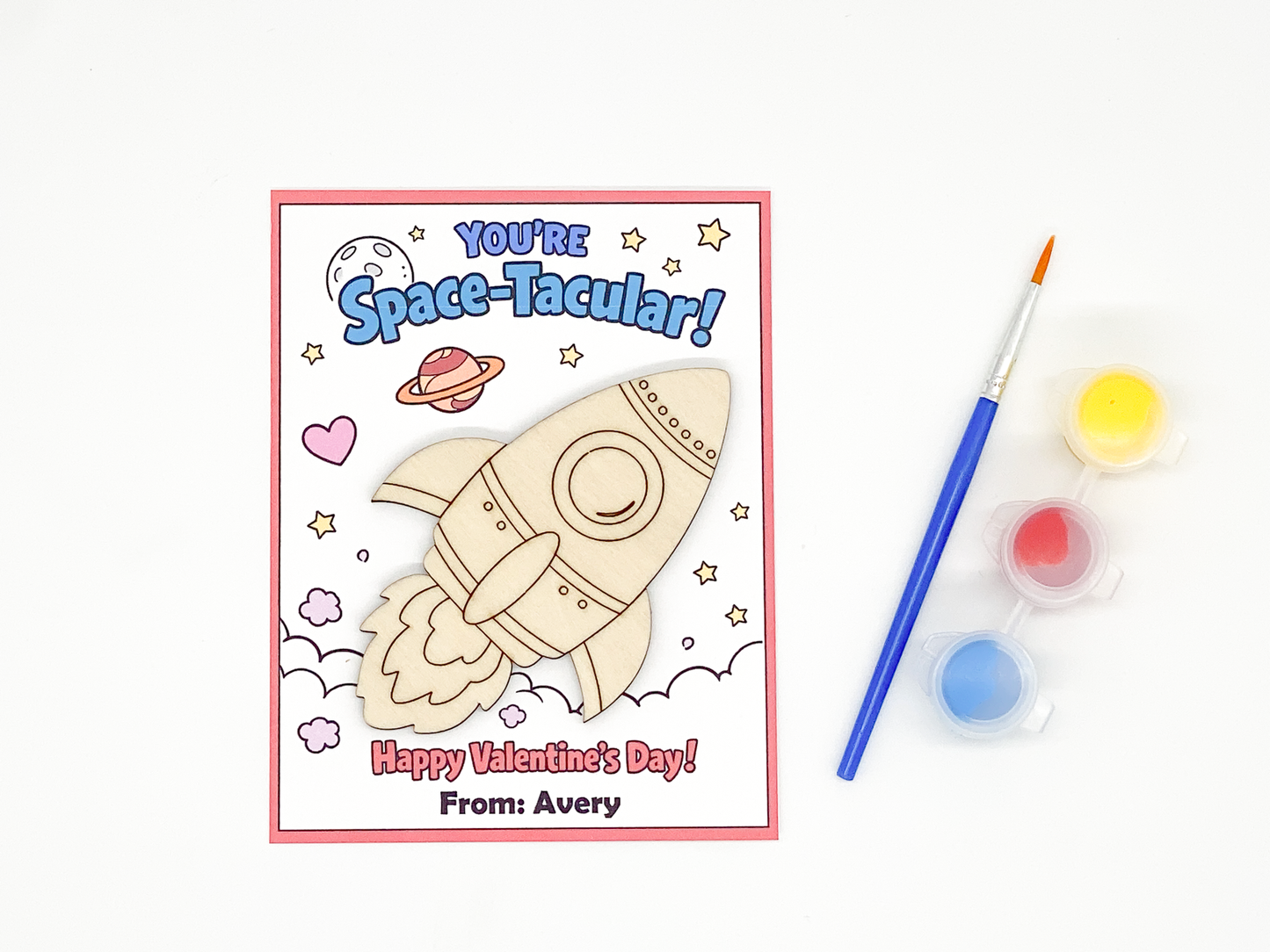 Valentine's Day card with a rocket design, paintbrush, and paint containers on a white background